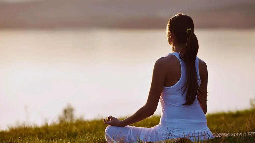 Yogini meditating near rishikesh river