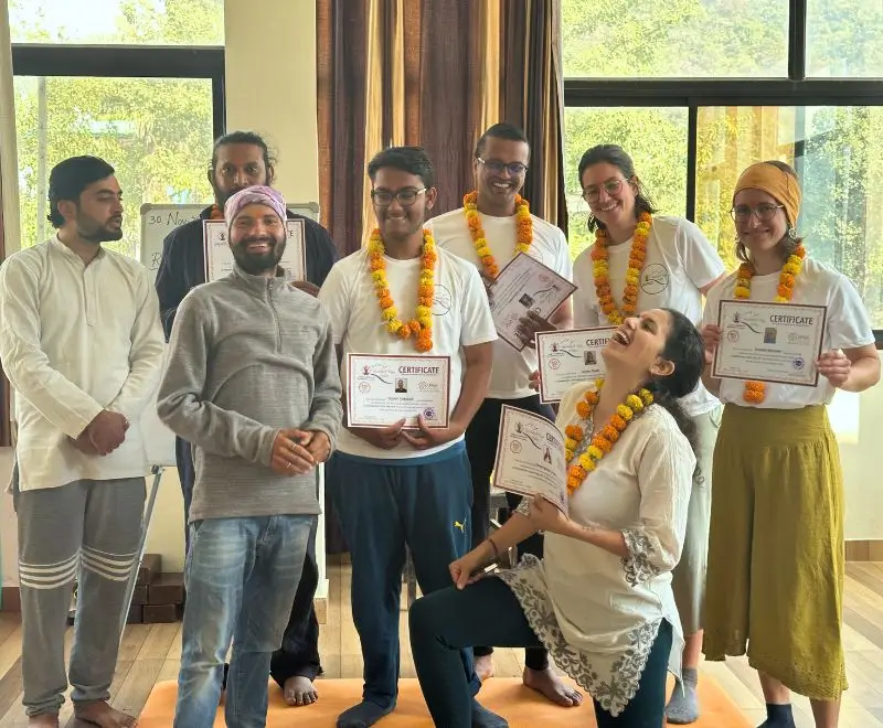 Smiling yoga students celebrating their graduation ceremony after completing the 200 Hour Yoga Teacher Training in Rishikesh, India, at Rishikesh Yoga Valley.