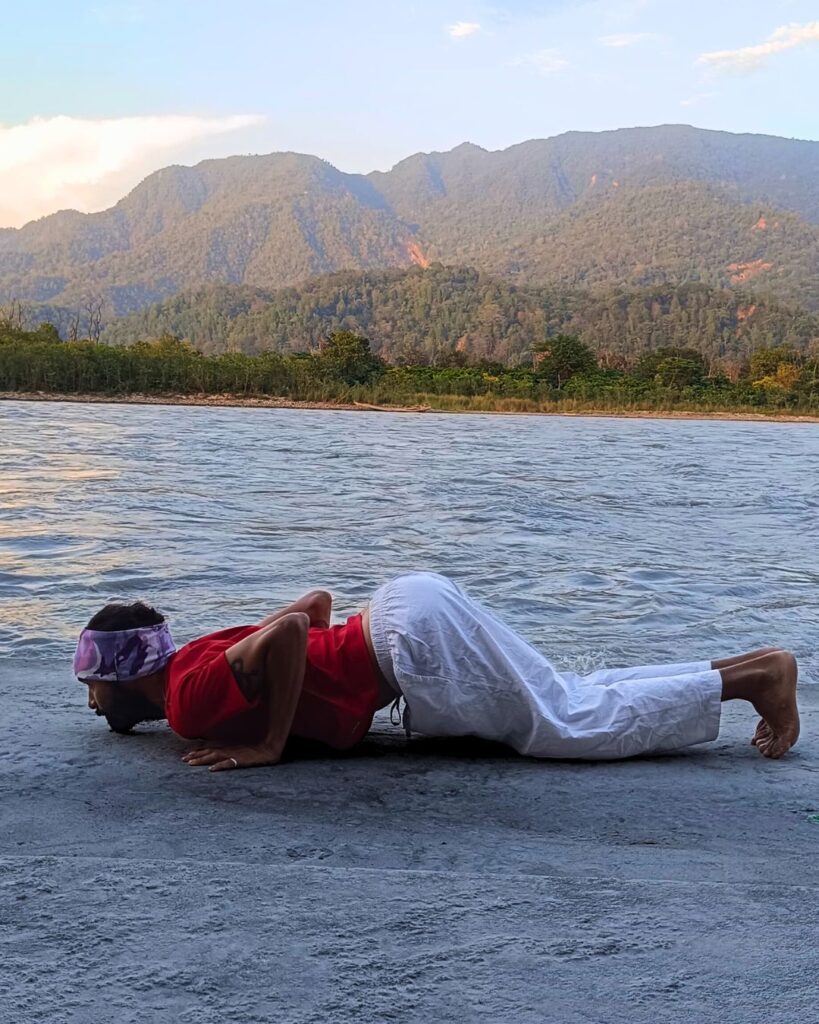 A person lowering knees, chest, and chin to the floor in Ashtanga Namaskara