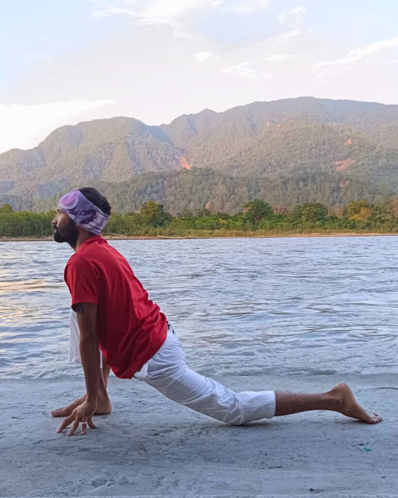 A person in low lunge with right foot forward, left knee on ground, hands beside right foot.