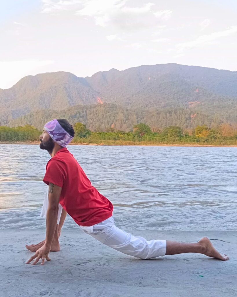 A person in low lunge with right foot forward, left knee on ground, hands beside right foot.