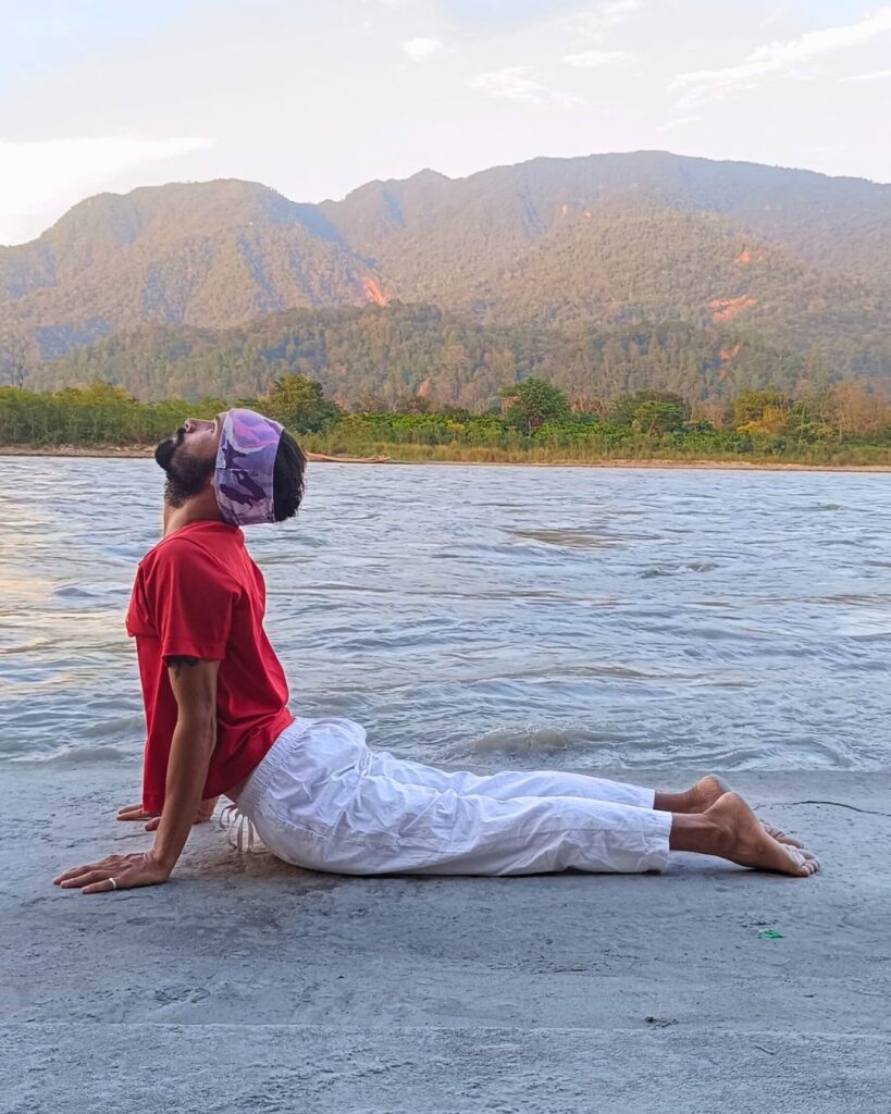 A person lying face down, chest lifted and arms straight in Cobra pose.