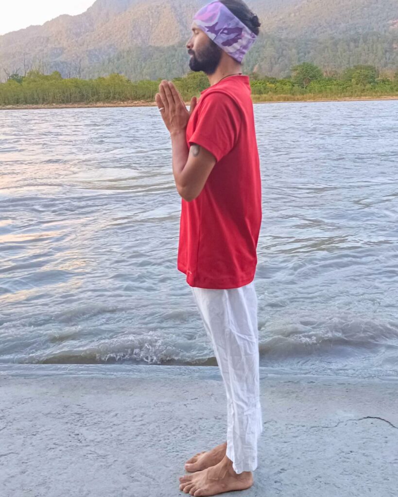 A person standing straight with arms at sides, completing the Sun Salutation.