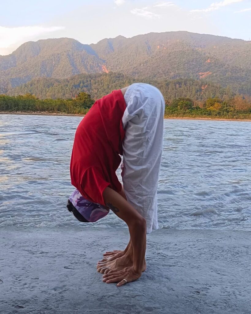 A person folding forward with hands reaching toward the floor in standing forward bend.