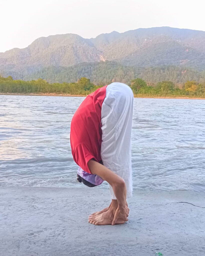 A person folding forward again with hands reaching toward feet in a standing forward bend.