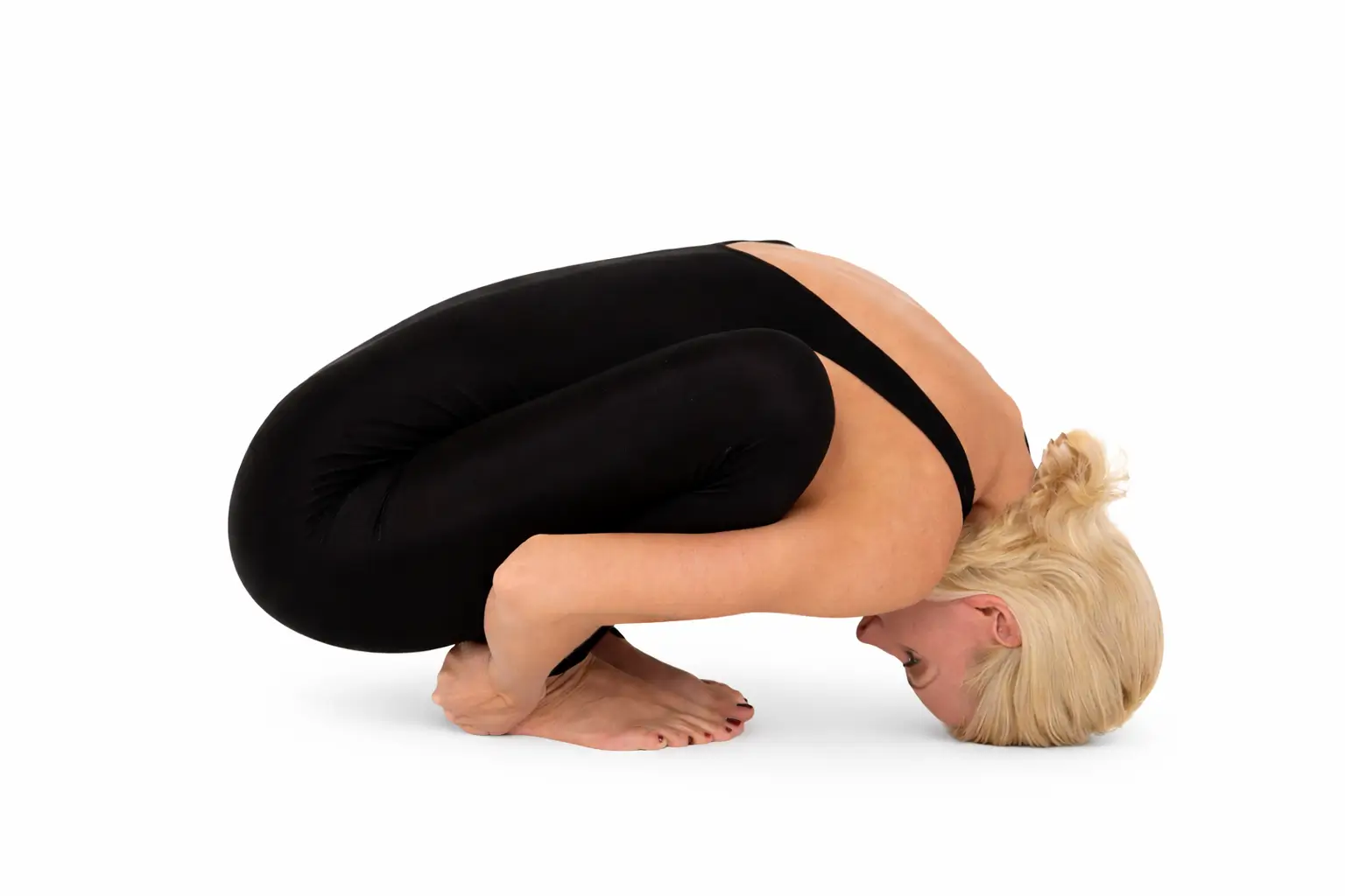 Woman performing Malasana Garland Pose deep yoga squat with heels grounded and forehead touching floor side view