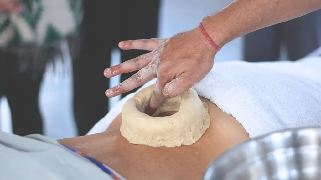 Close-up of an Ayurvedic therapist preparing a dough dam for oil treatment at a 10 days Ayurveda and yoga retreat in Rishikesh India.