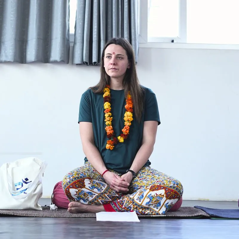 A student in a flower garland meditating during a 100 hour yoga teacher training in Rishikesh India.