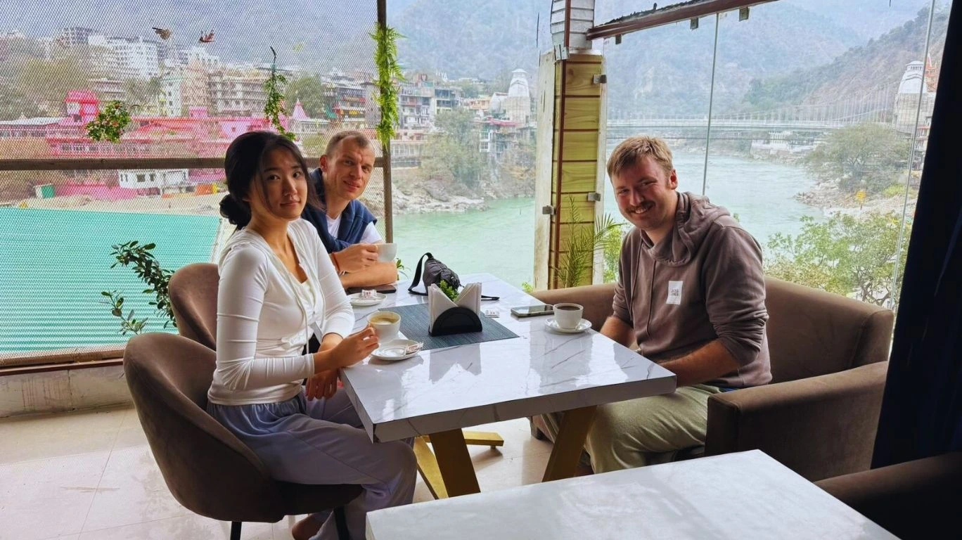 Yoga students enjoying tea with Ganga river view during 50 hour yoga teacher training in Rishikesh, India.