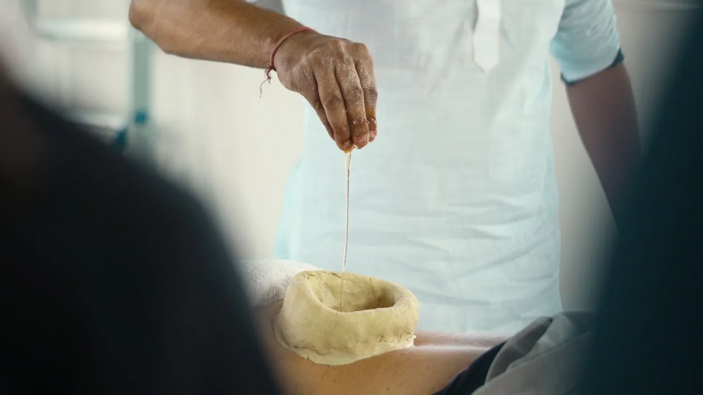Ayurvedic therapist performing Kati Basti oil treatment at a 7 days Ayurveda and yoga retreat in Rishikesh India.