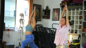 Two students practicing lunges in a studio, demonstrating that any student who are not flexible can join yoga TTC guide and succeed in professional training