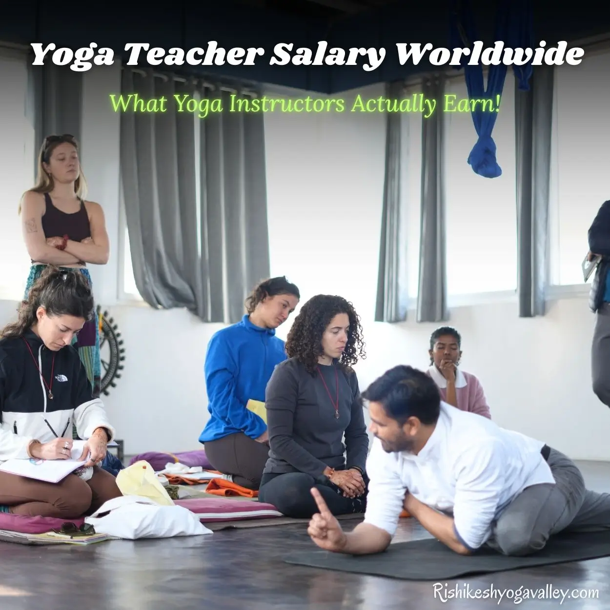 A yoga teacher training session at Rishikesh Yoga Valley with the overlay text "Yoga Teacher Salary Worldwide: What Yoga Instructors Actually Earn!" The image shows a lead instructor demonstrating a pose to students who are taking notes, highlighting the professional path of a traditional yogic lifestyle.