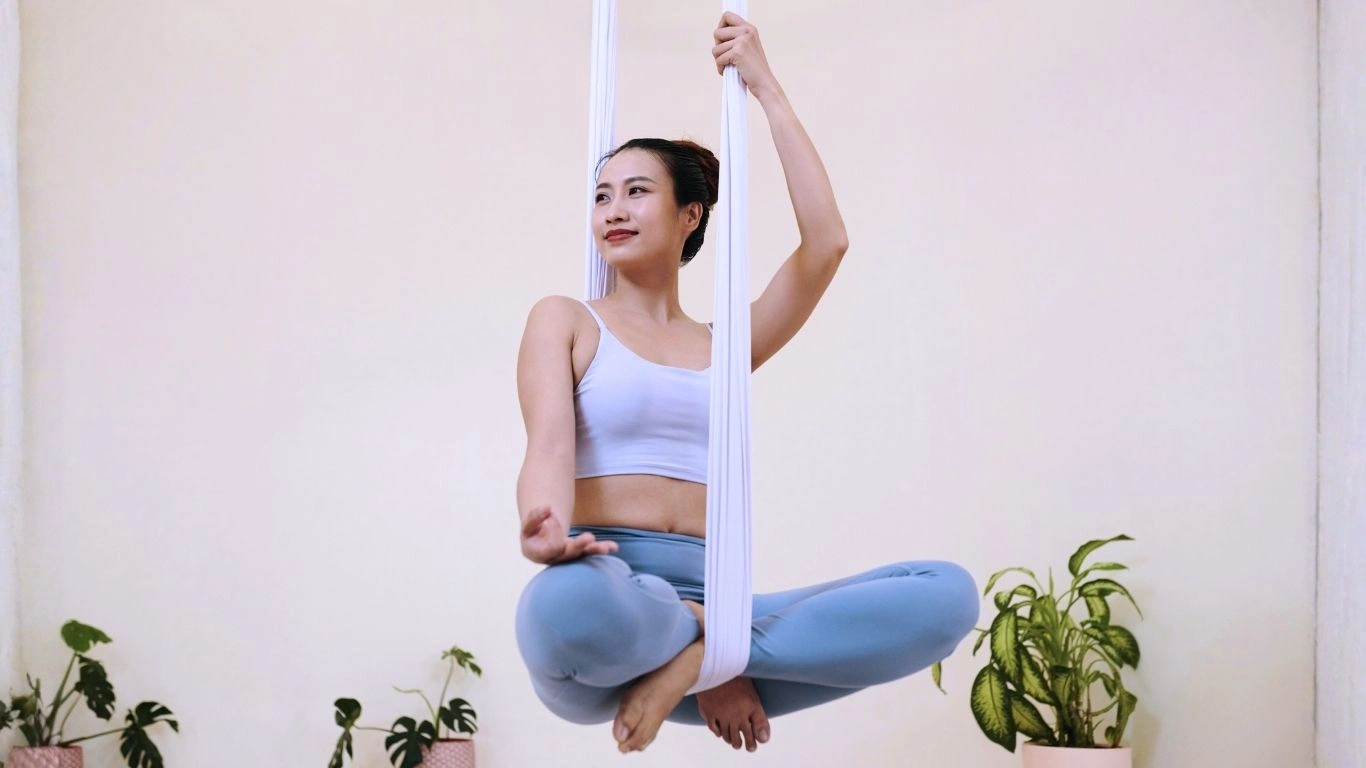 Student practicing aerial hammock pose during aerial yoga teacher training in Rishikesh.