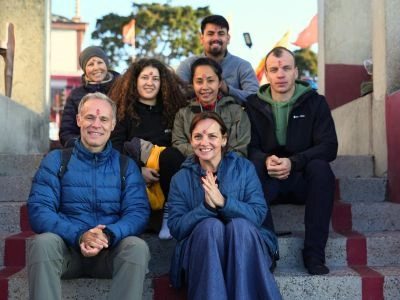 A diverse group of happy participants posing on temple steps during one of the best Ayurveda retreats in Rishikesh, India.