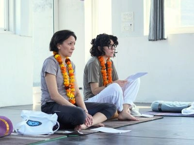 Two female students wearing traditional flower garlands participating in a workshop at one of the best Ayurveda retreats in Rishikesh.