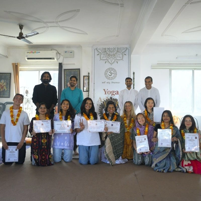 Happy international graduates holding their yoga certificates alongside their teachers at the conclusion of a 100 hour Kundalini yoga teacher training in Rishikesh, India.