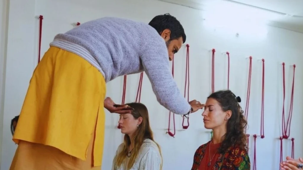Yoga teacher giving forehead blessing to international students during meditation session in a yoga class