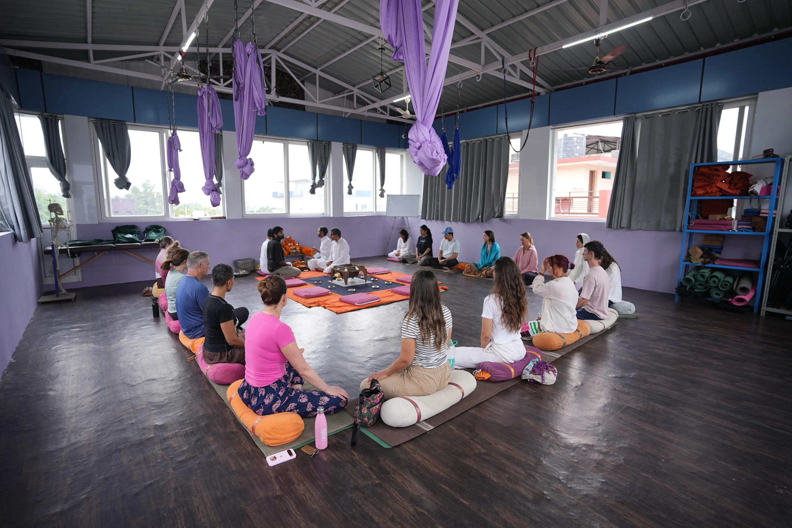 Yoga teacher training students sitting in a circle during an indoor class session at a yoga school in Rishikesh, India.