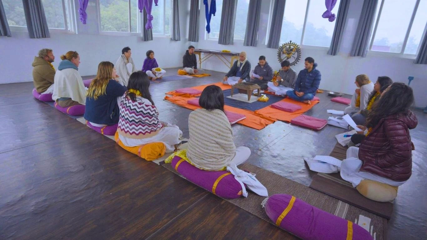 Yoga teacher training students participating in a traditional spiritual ritual class inside a yoga school in Rishikesh, India.