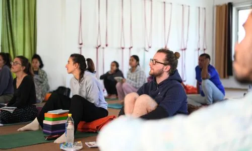 Students attending group learning session during 50 hour yoga teacher training in Rishikesh India inside a traditional yoga studio