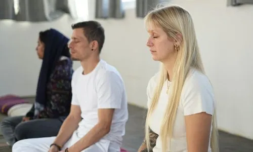 Students practicing group meditation during 50 hour yoga teacher training in Rishikesh India inside a peaceful yoga studio