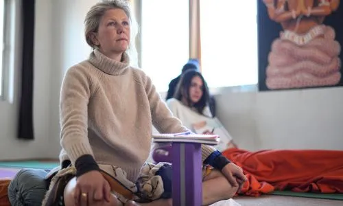 Student practicing mindfulness meditation during 50 hour yoga teacher training in Rishikesh India inside a traditional yoga studio