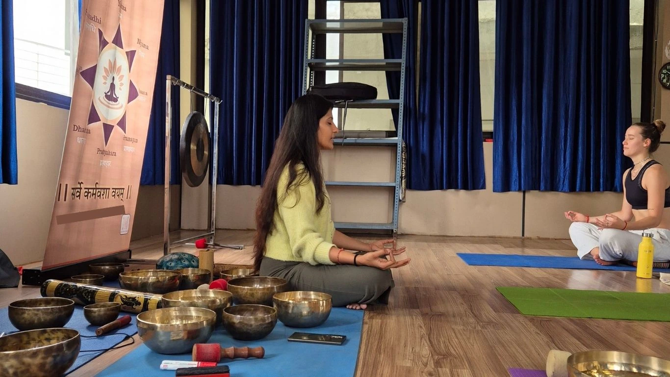 Sound healing meditation session with Tibetan singing bowls and yoga practitioners practicing mindfulness and relaxation at Rishikesh Yoga Valley.