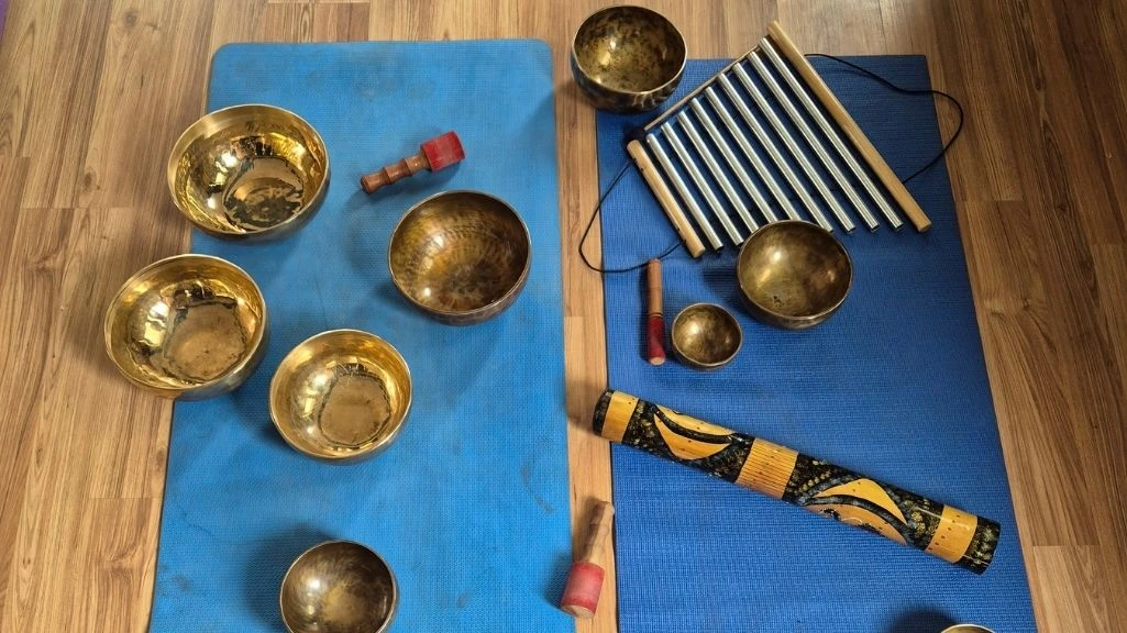 Tibetan singing bowls, chimes, and sound healing instruments arranged on yoga mats for meditation, relaxation therapy, chakra balancing, and holistic wellness practices