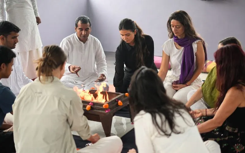 Students and teachers participating in a traditional sacred fire ceremony during a 200 hour Kundalini Yoga Teacher Training in Rishikesh India.
