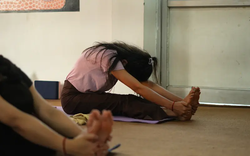 Student practicing Paschimottanasana during a 500 hour Yoga Teacher Training in Rishikesh India.