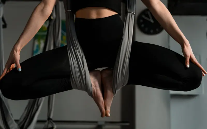 A student practicing a suspended pose during aerial yoga teacher training in Rishikesh.