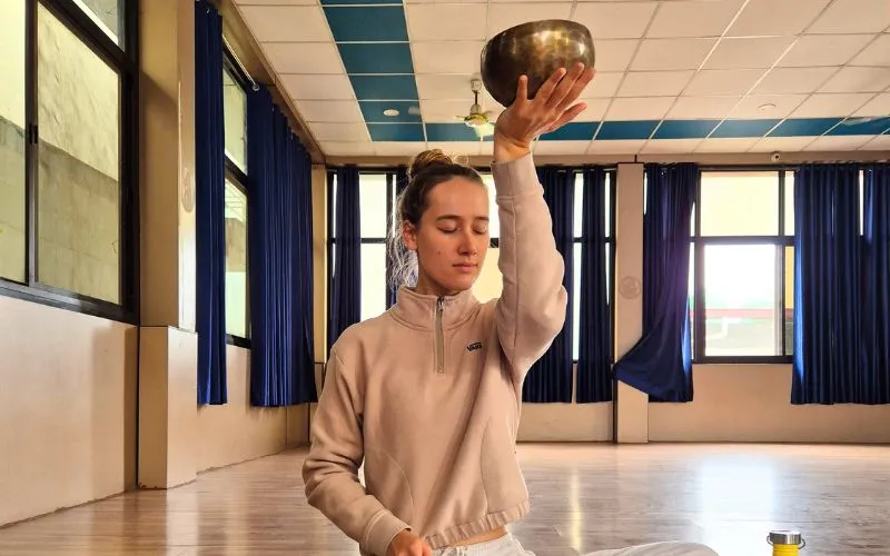 Student practicing Tibetan singing bowl meditation during a sound healing training course in Rishikesh.