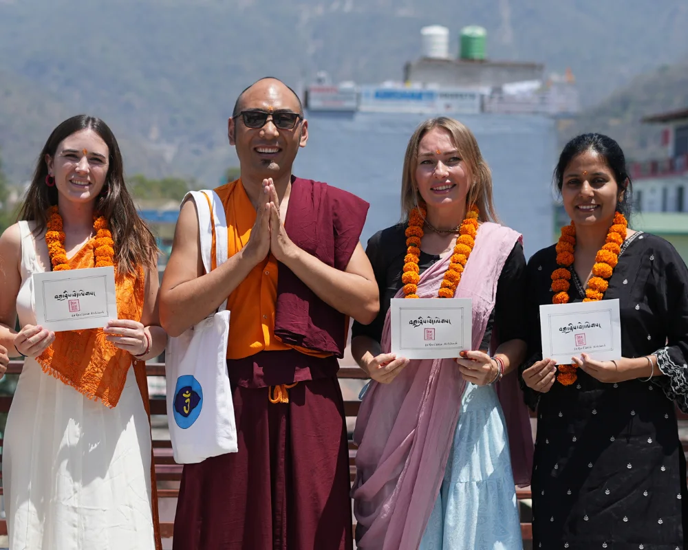 Graduates holding certificates with marigold garlands at a 100 hour yoga teacher training in Rishikesh.