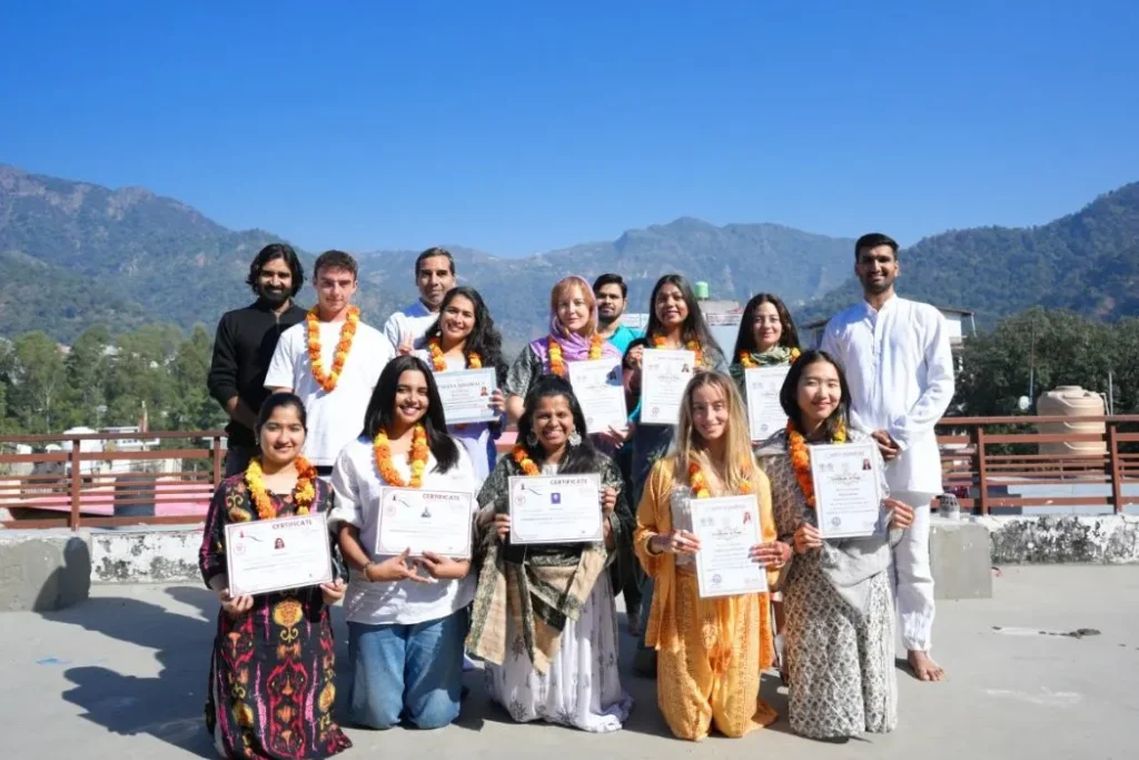 Proud graduates of Rishikesh Yoga Valley holding up their international yoga alliance certification diplomas.