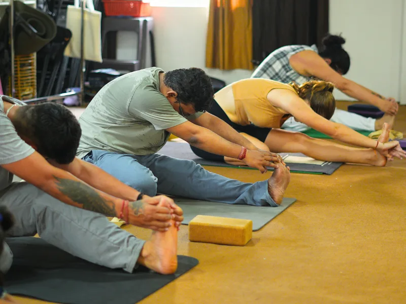 Participants practicing seated forward stretches during a 10 Days Yoga Retreat in Rishikesh