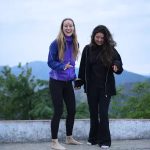 Two happy yoga students laughing and enjoying outdoor mountain views together during the 200 hour Kundalini yoga teacher training in Rishikesh.
