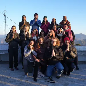 Group of yoga students and teachers posing with namaste hands in the mountains during a 100 hour yoga teacher training in Rishikesh