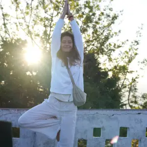 Yoga practitioner performing tree pose outdoors in the sunlight during a 100 hour yoga teacher training in Rishikesh