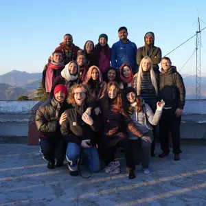 Large group of international yoga batch mates and instructors posing together on a scenic outdoor terrace during a 300 hour yoga teacher training in rishikesh excursion.