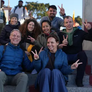 A diverse group of international yoga students with tilak on their foreheads making peace signs together outdoors during a 300 hour yoga teacher training in rishikesh excursion.