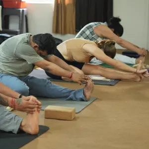 Yoga students practicing seated forward bend (Paschimottanasana) on yoga mats during 50 hour yoga teacher training in rishikesh.