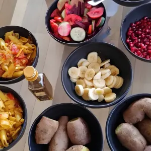 Fresh sattvic meals served in black bowls including sliced fruits, fresh salad, penne pasta, and sweet potatoes during 50 hour yoga teacher training in rishikesh
