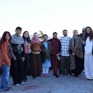 Group of international yoga students standing together outdoors on a rooftop terrace during a 50 hour yoga teacher training in rishikesh.