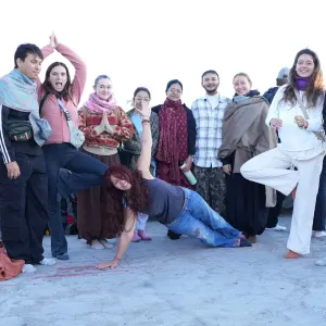 Group of yoga students holding tree pose and side plank variations together outdoors during a 500 hour yoga teacher training in rishikesh excursion.