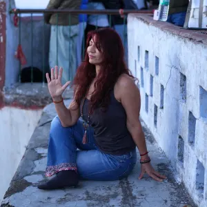 Female yoga student with eyes closed practicing Half Lord of the Fishes pose (Ardha Matsyendrasana) seated outdoors during a 500 hour yoga teacher training in rishikesh.
