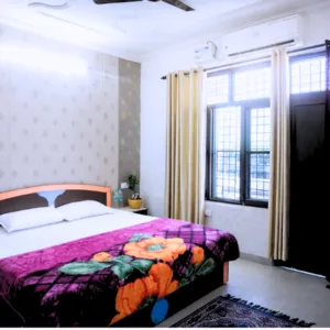 Spacious private bedroom with double bed, air conditioning, and large window providing modern accommodation for a 500 hour yoga teacher training in rishikesh student.