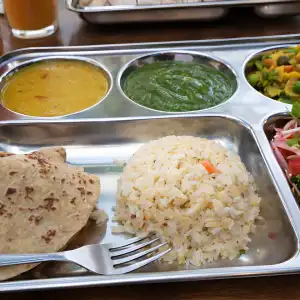 A traditional Indian thali plate with rice, chapati, dal, chutney, and fresh vegetables served during a 500 hour yoga teacher training in rishikesh course.