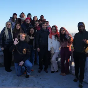 A group of smiling international yoga teacher training students and teachers posing outdoors during a 500 hour yoga teacher training in rishikesh mountain trip.