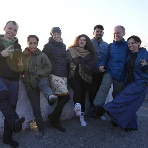Group of happy international yoga students kicking up their feet and posing joyfully together during an outdoor excursion in a 500 hour yoga teacher training in rishikesh.