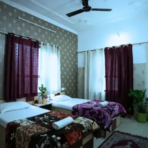Cozy and clean twin-sharing student accommodation room with single beds, blankets, and natural sunlight for 500 hour yoga teacher training in rishikesh attendees.